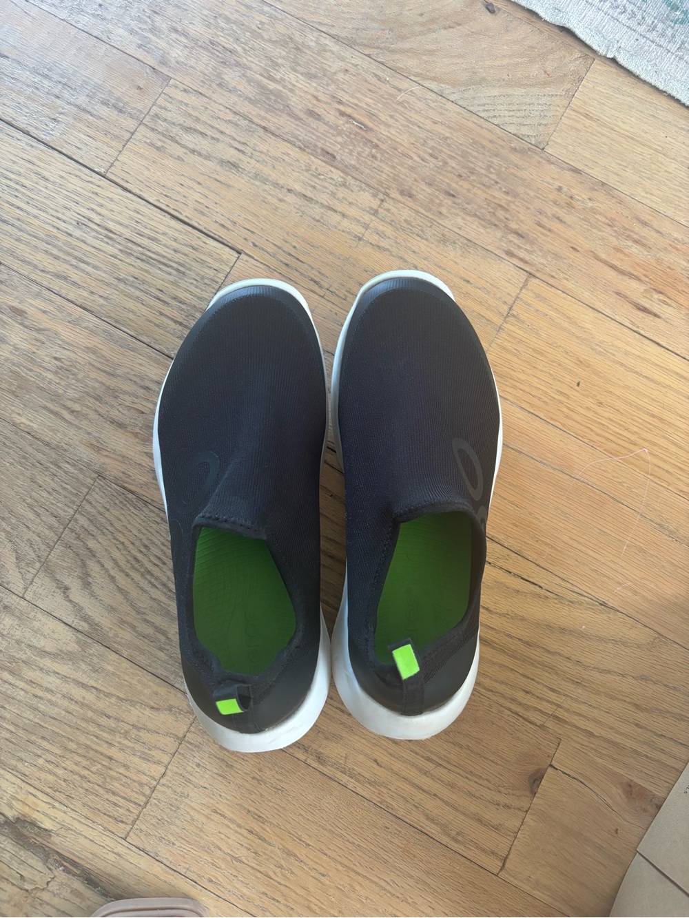 OOFOS Women’s Slip-On Sneakers in Black with Bright Green Insoles